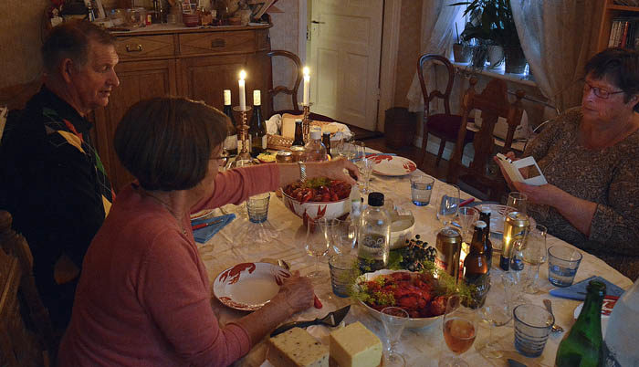 Se nu har kräftorna kommit på bordet. Resursmatte sitter och leker med sin telefon, men snart ger hon sig hän åt kräftorna.